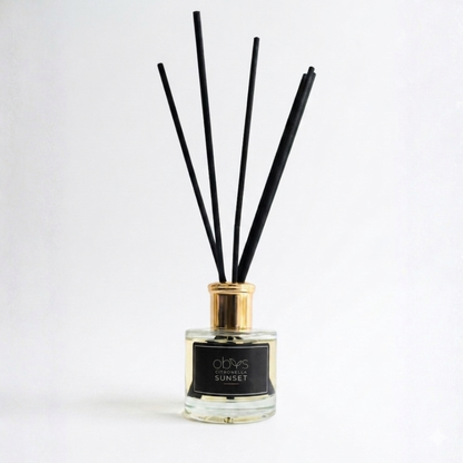 Reed diffuser with black sticks in a glass bottle on a white background