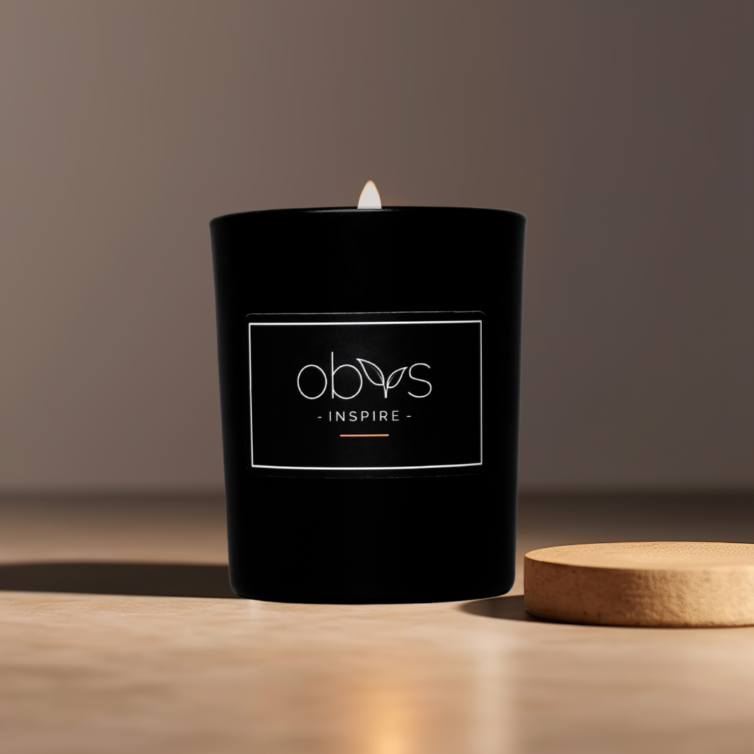 A matte black candle jar filled with organic essential oils, burning with a soft, warm flame. The minimalist design exudes elegance, while the gentle aroma from natural essential oils creates a calming, eco-friendly atmosphere. The candle sits on a wooden surface, with subtle shadows enhancing its luxurious, earthy vibe, perfect for relaxation or meditation