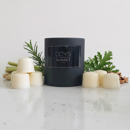 Black wax melt container labeled 'Citronella Sunset' on a marble surface with decorative elements.