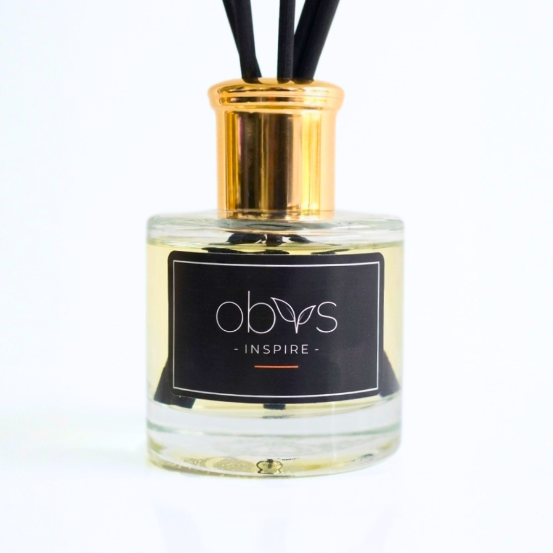 A clear glass diffuser bottle with a gold cap and black label on a white background