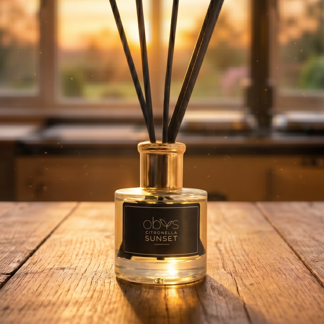 Reed diffuser labeled 'Citronella Sunset' on a wooden surface with a blurred background
